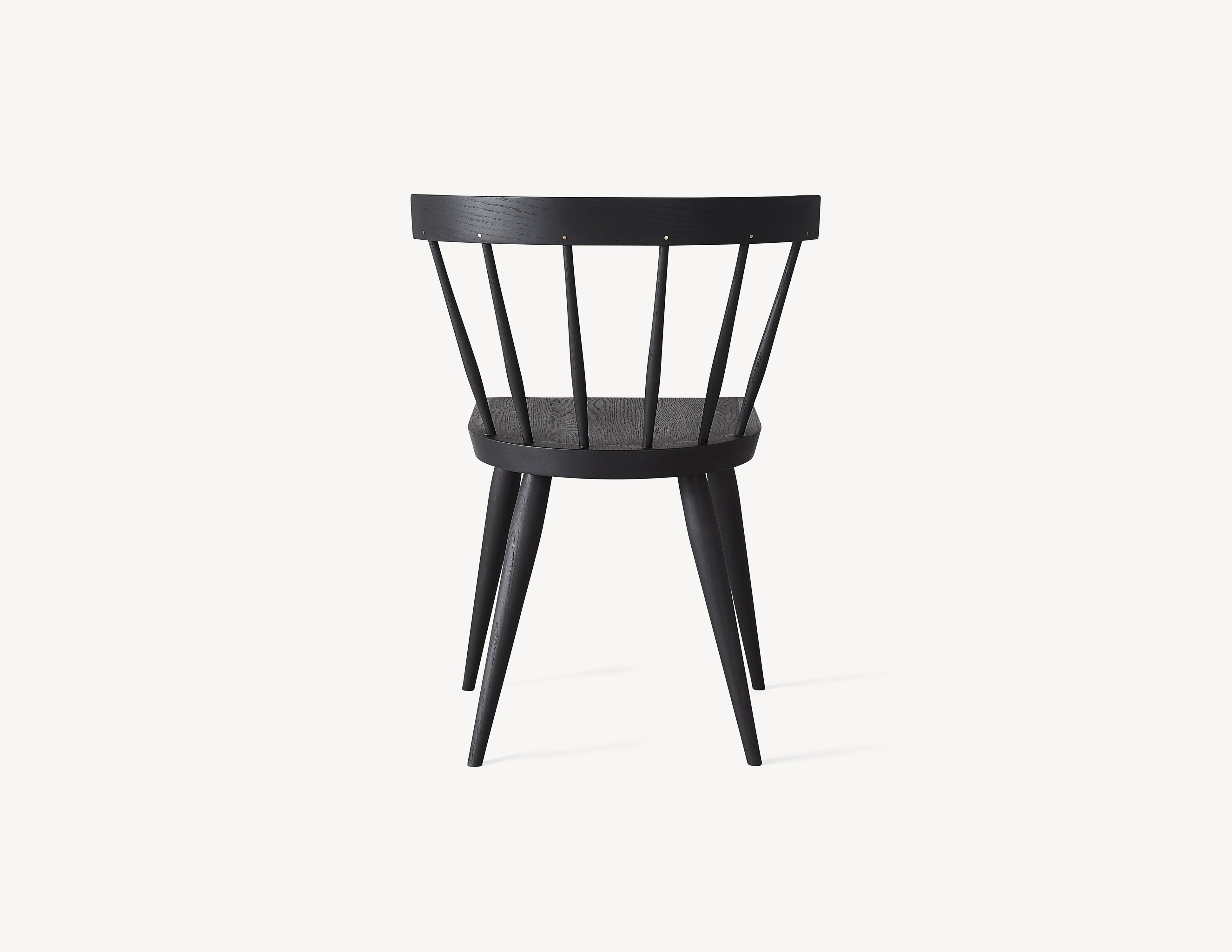 rear view of minimal black wooden windsor dining chair with brass details.