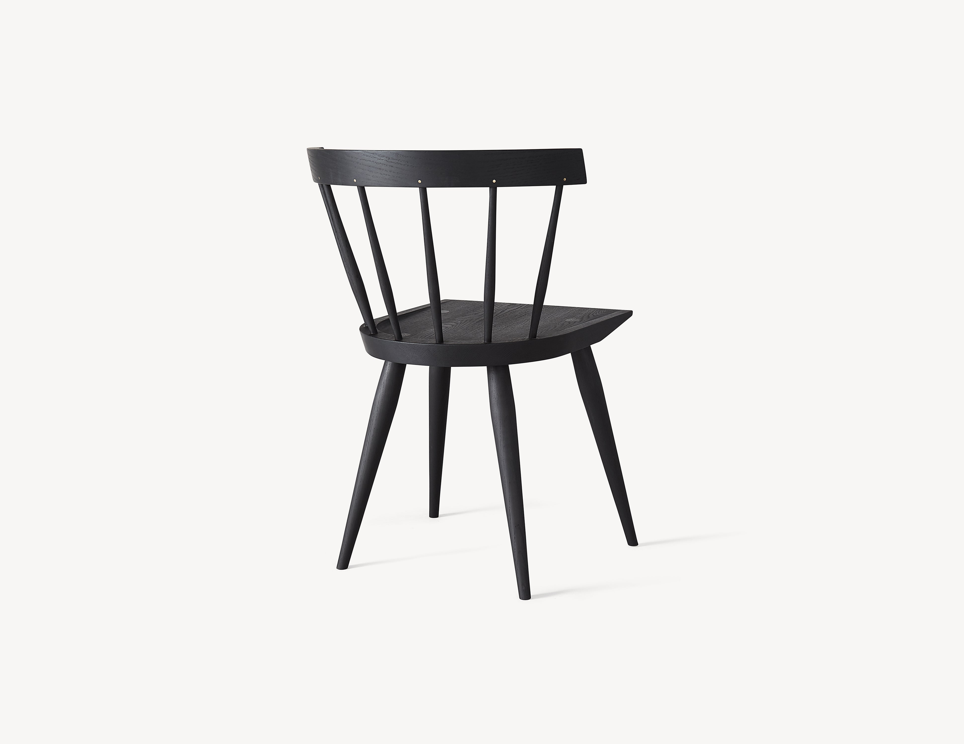 minimal black wooden windsor dining chair with brass details, three quarter view.