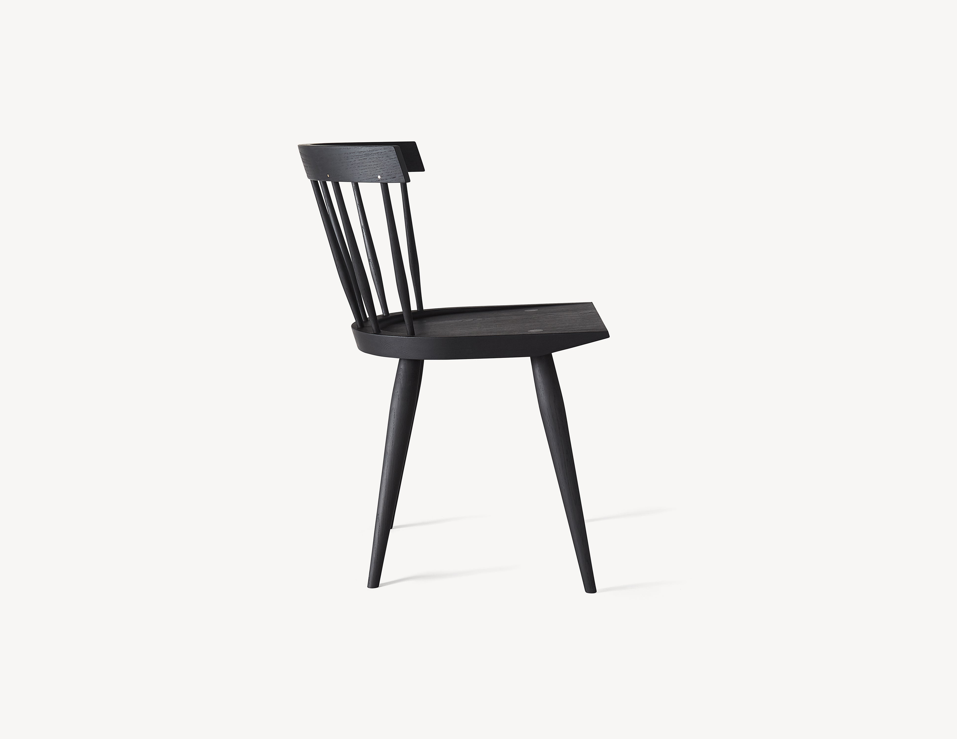 side view of minimal black wooden dining chair with brass details.