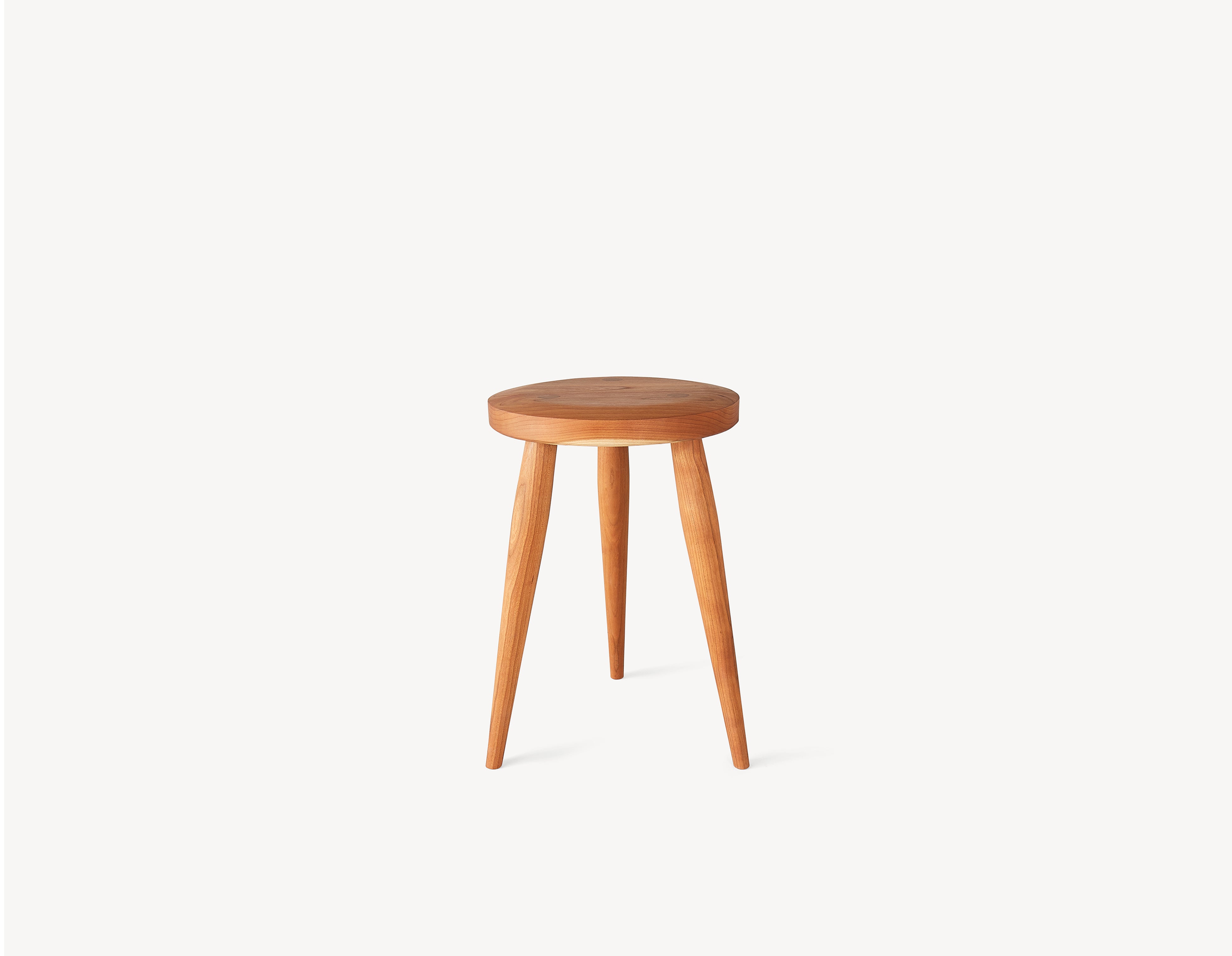 Three-legged brown milking stool with turned legs and a circular seat in brown cherry wood