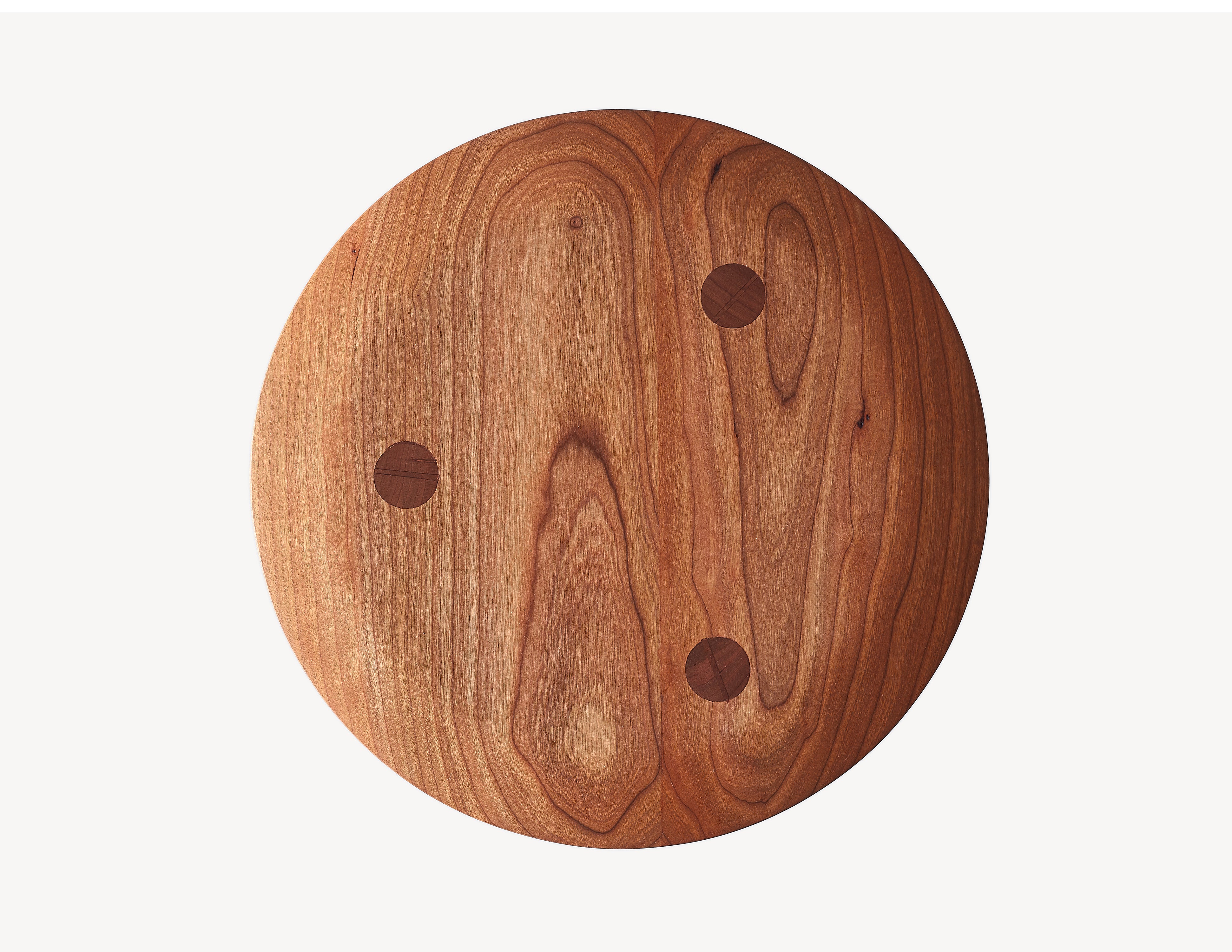 Top view of a three-legged brown milking stool with turned legs and a circular seat in brown cherry wood