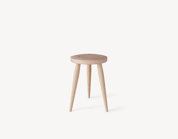 Three-legged oak milking stool with turned legs and a circular seat in light wood.