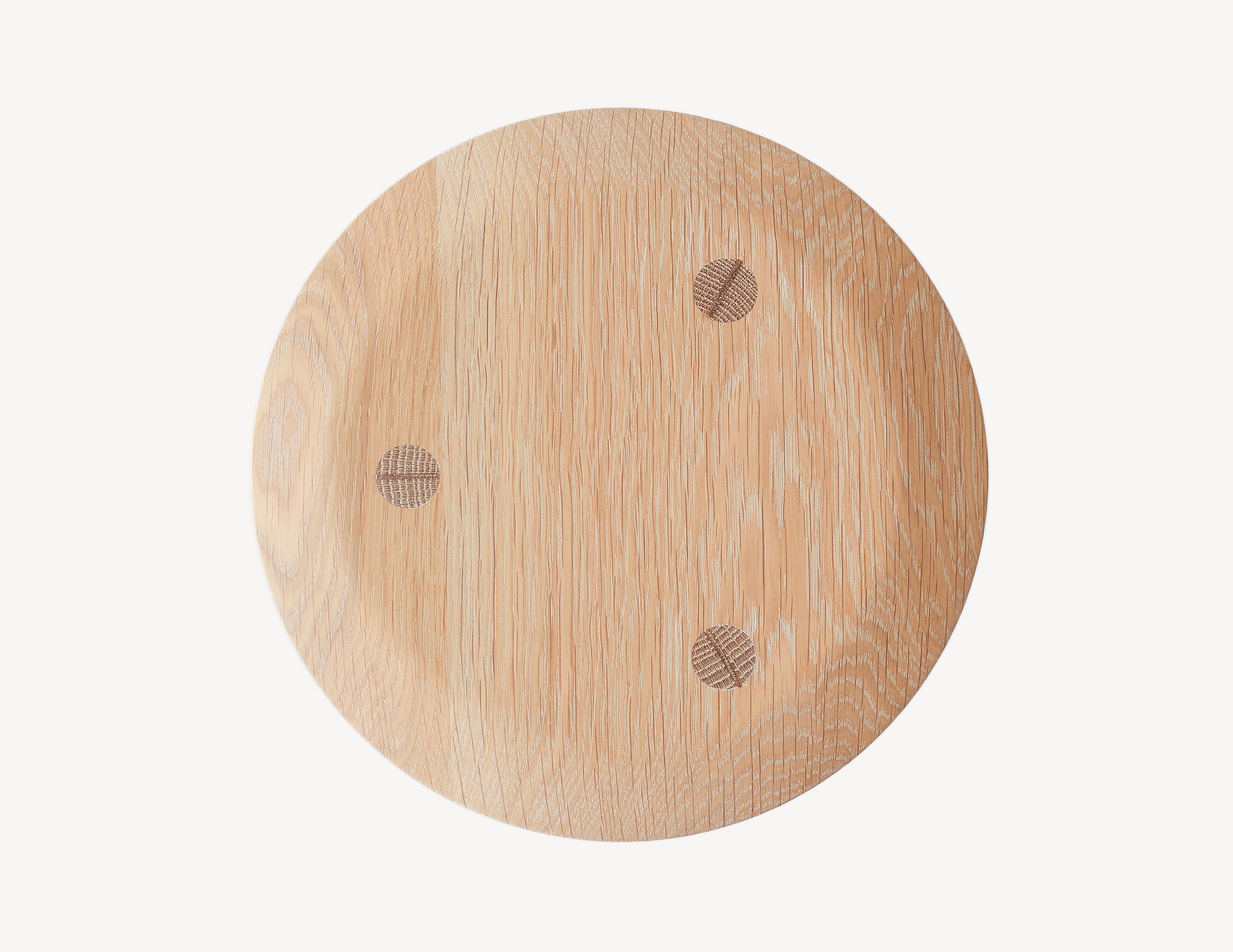 Top view of a three-legged oak milking stool with turned legs and a circular seat in light wood