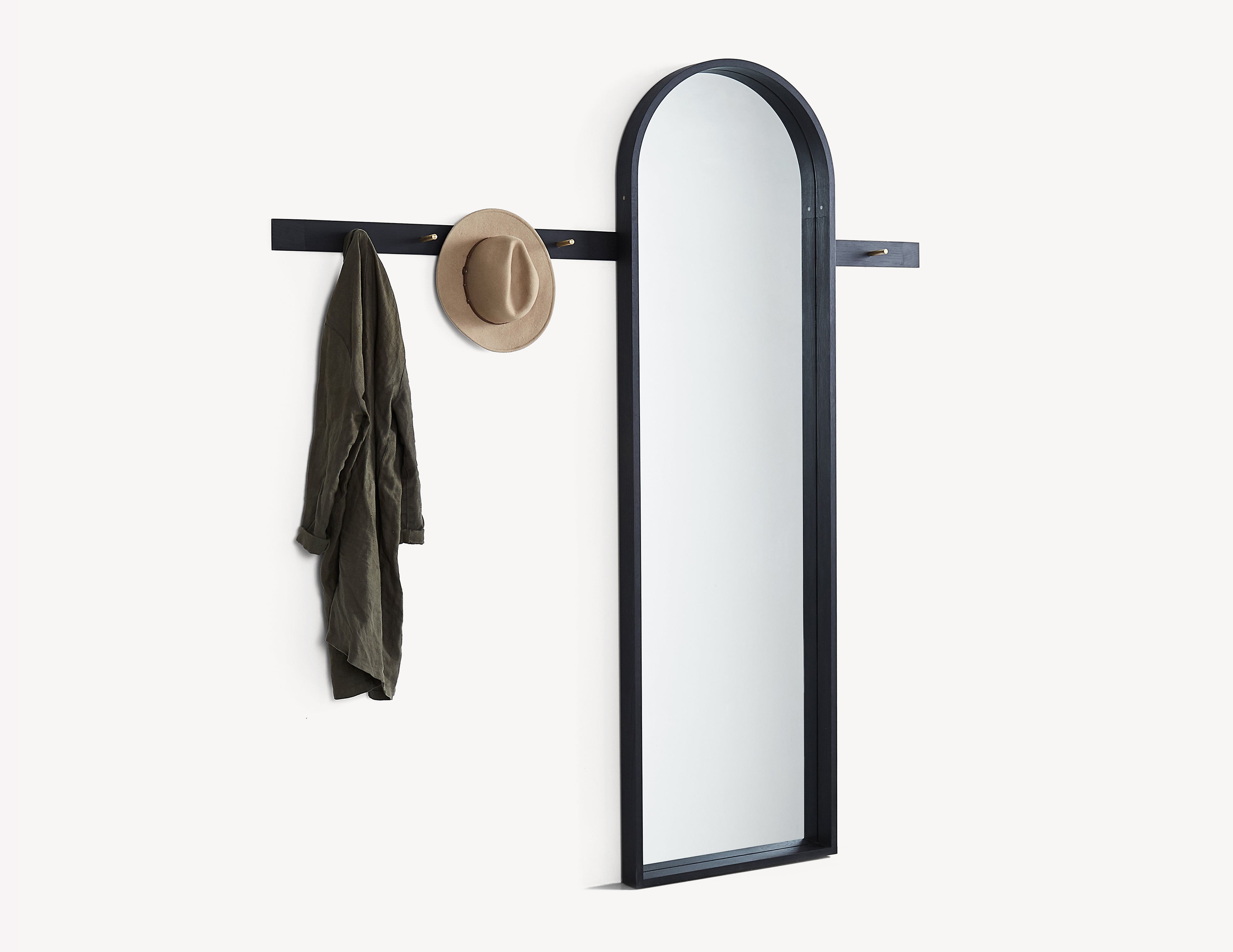 black wood rail in oak with brass pegs, with a full-length black mirror.  a hat and coat hanging on the pegs.