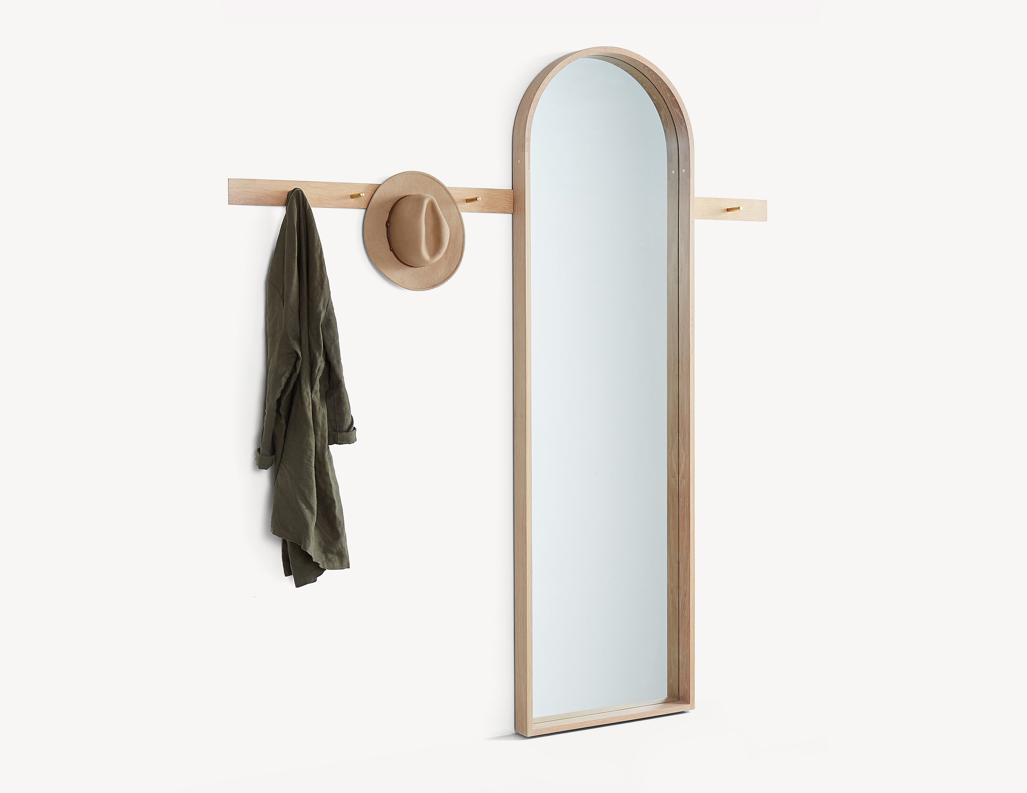light oak wood rail with brass pegs, with a full-length mirror.  a hat and coat hanging on the pegs.