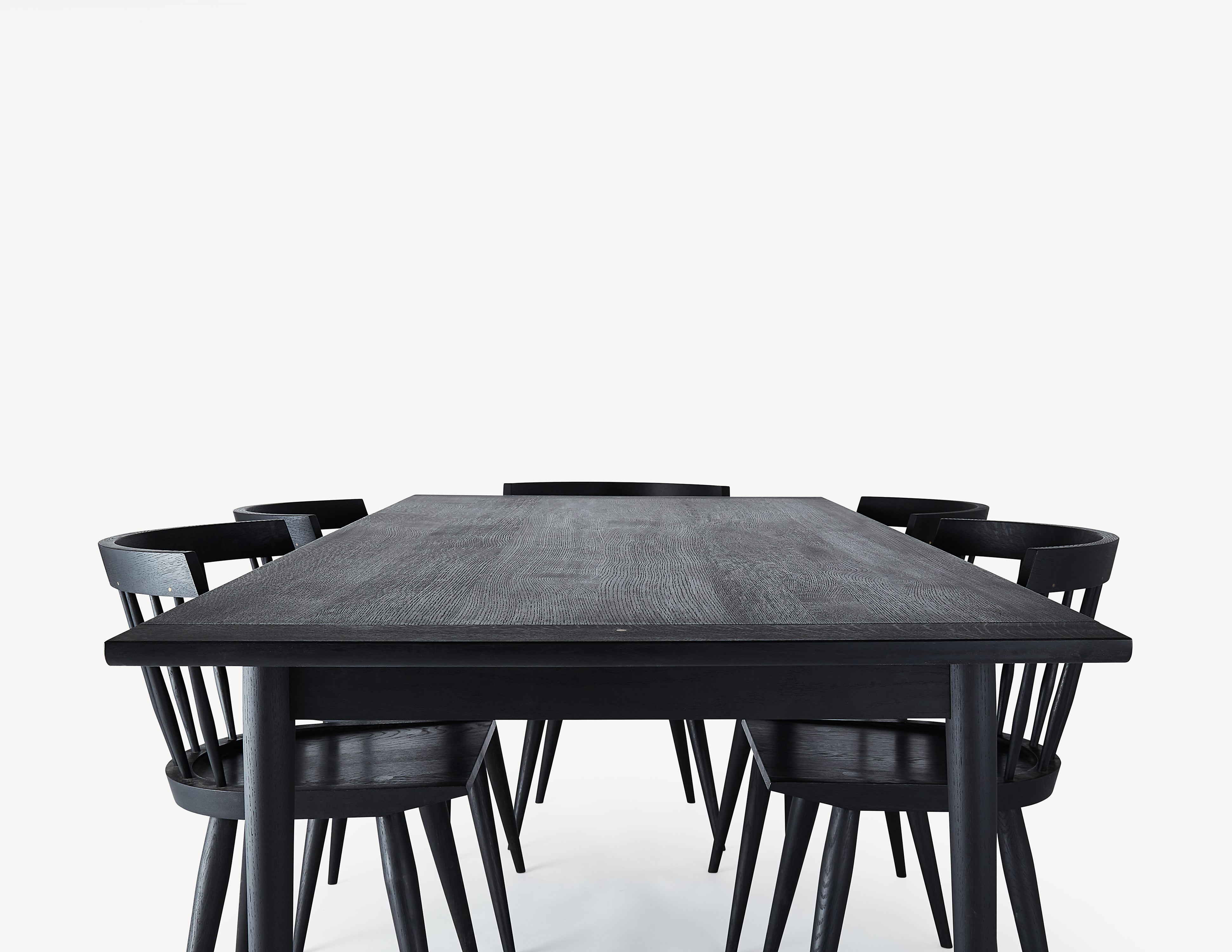 black wooden dining table with five minimal black wooden windsor dining chairs.