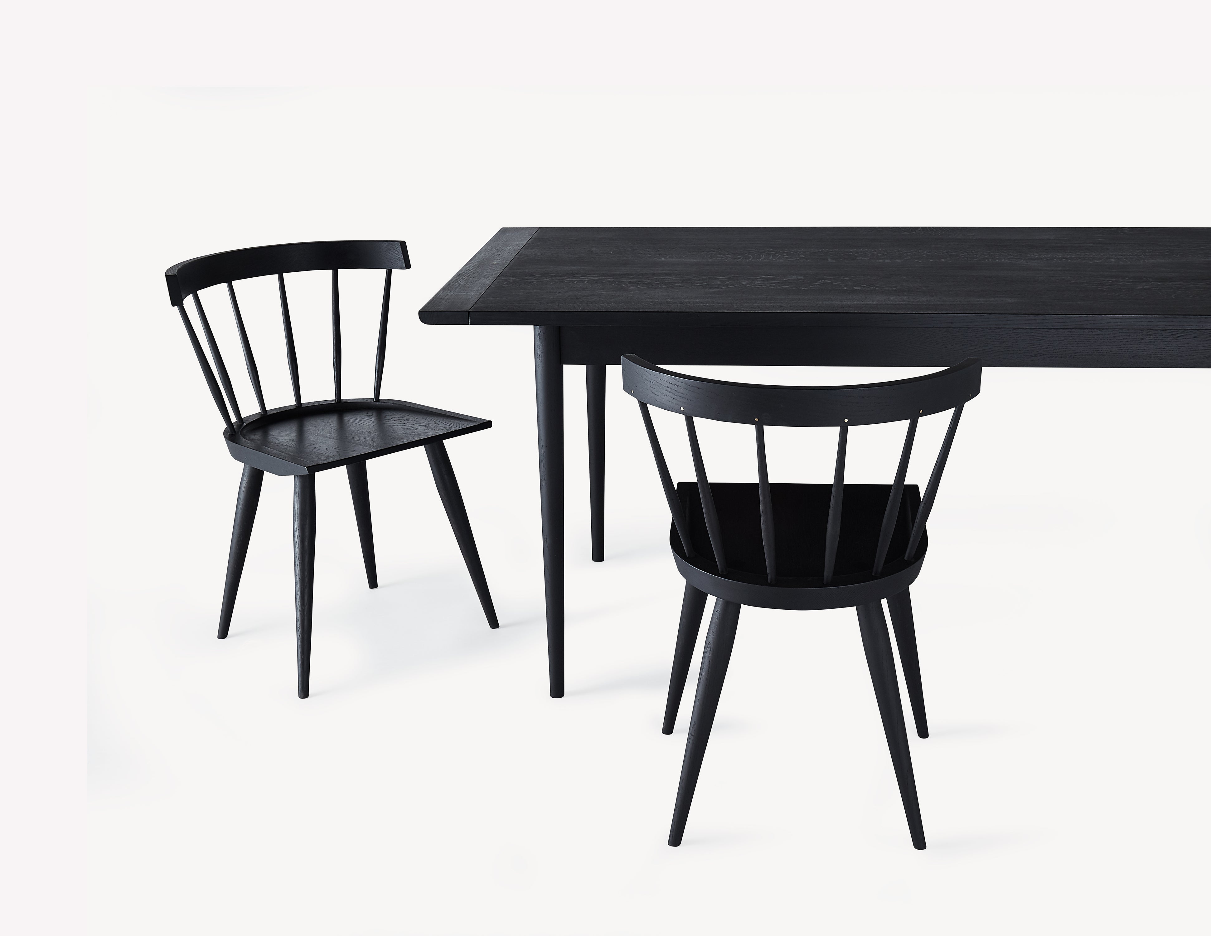 black wooden dining table with two minimal black windsor dining chairs.