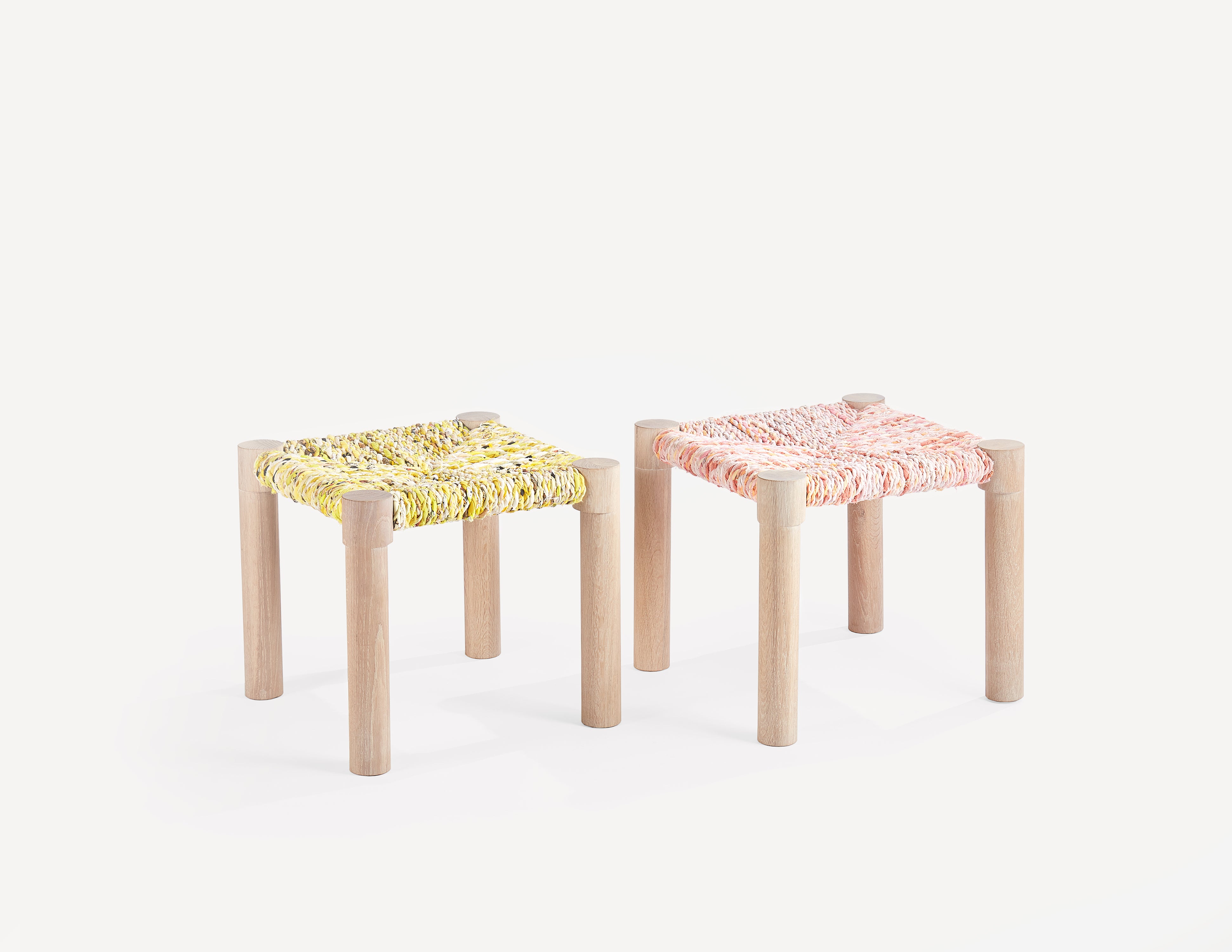 pair of wooden stools with woven seats - one pink and one yellow.